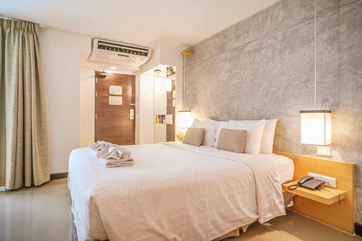Une chambre d’hôtel avec un grand lit, un téléphone sur la table de chevet et un climatiseur fixé au mur.