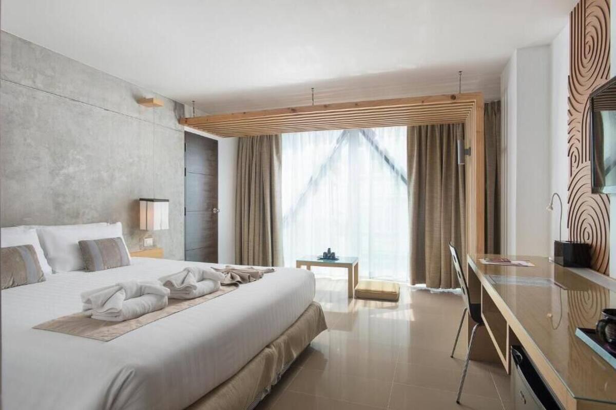 Une chambre d’hôtel moderne, dotée d’un grand lit, d’un bureau et offrant une vue sur l’extérieur.
