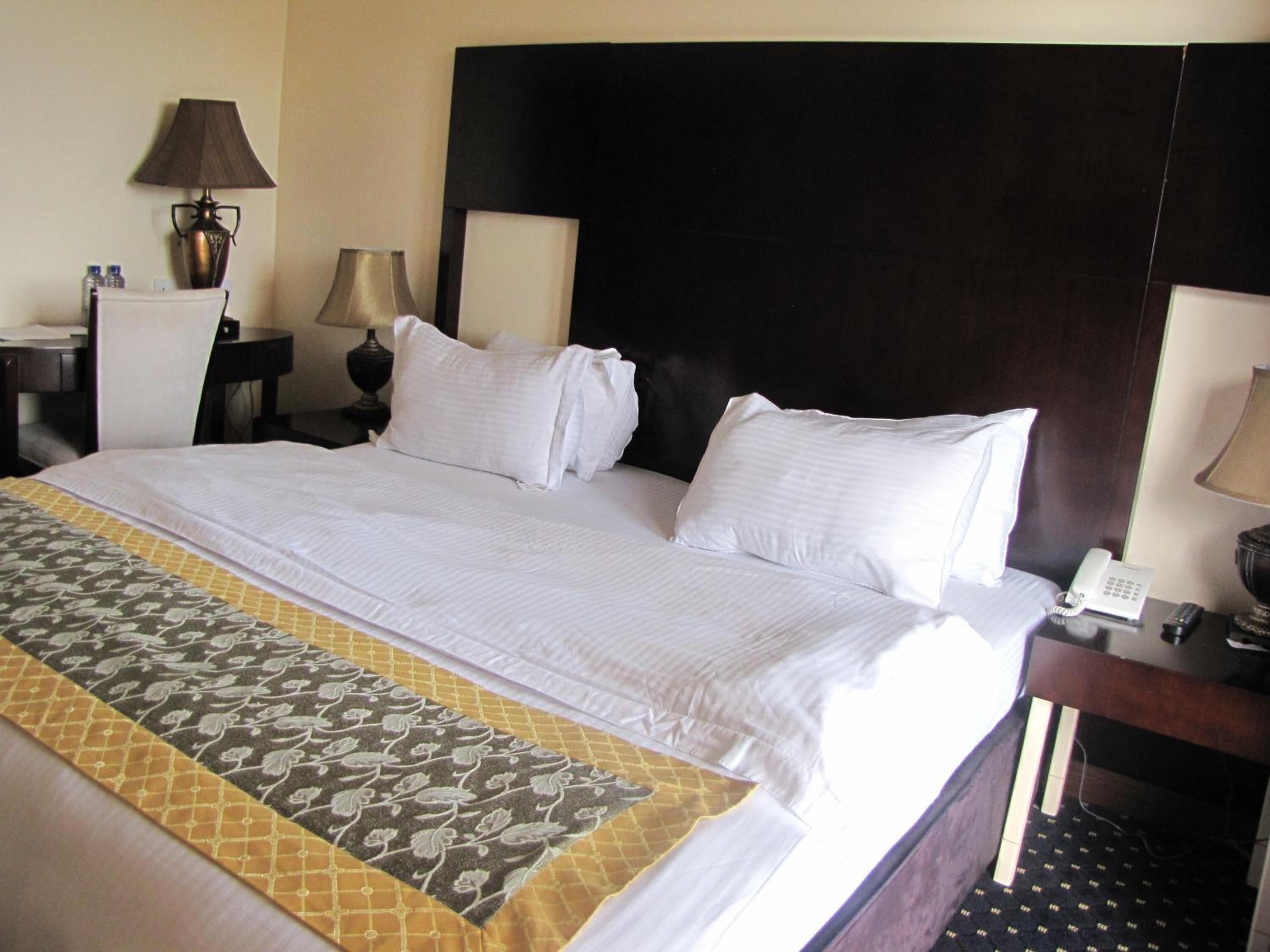 Habitación de hotel con una cama grande, dos mesitas de noche, una lámpara y un teléfono.