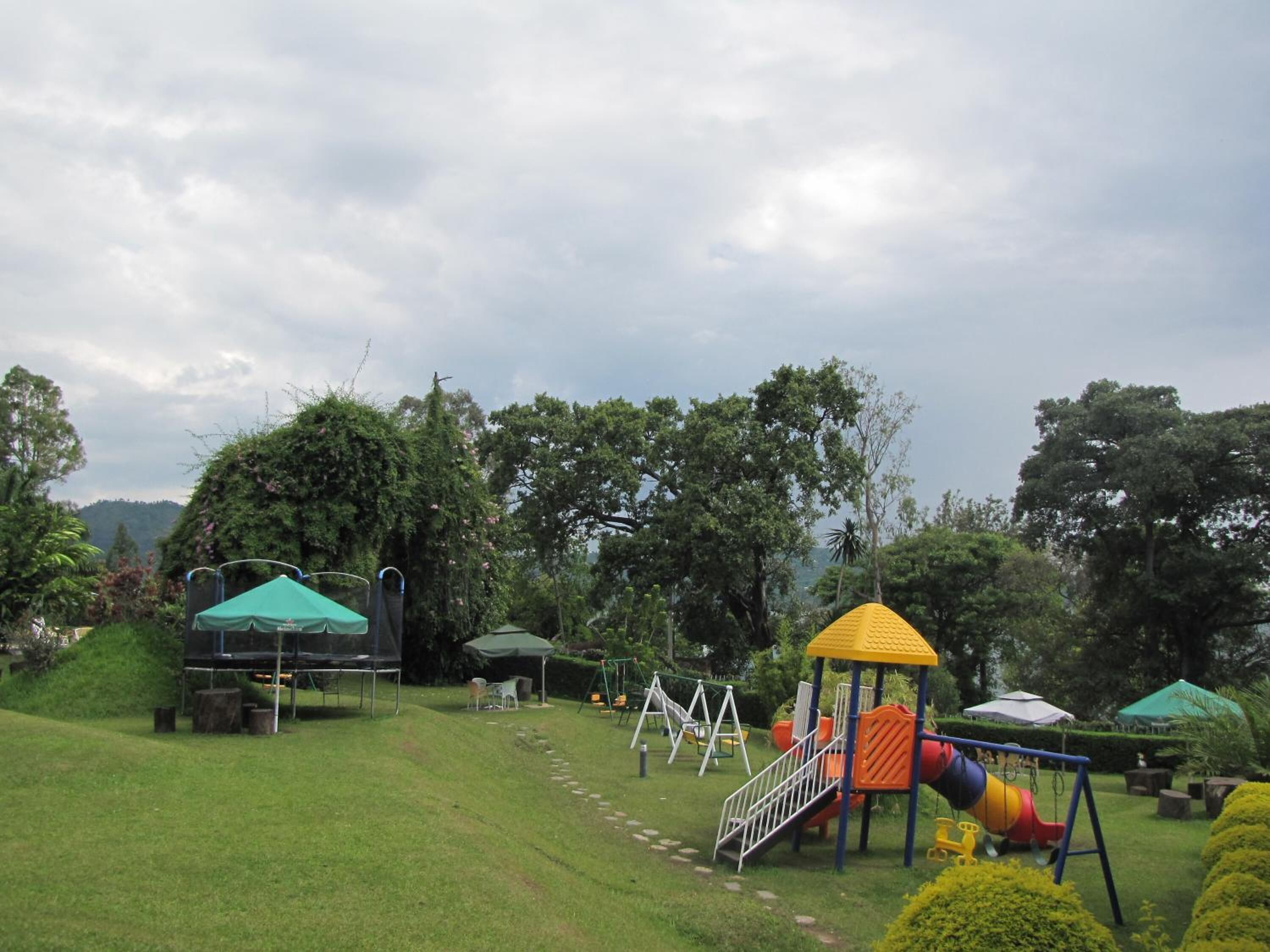 A playground with slides and swings, surrounded by green grass and trees.