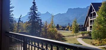 Vista de varanda com paisagem montanhosa e um edifício com design arquitetônico moderno.