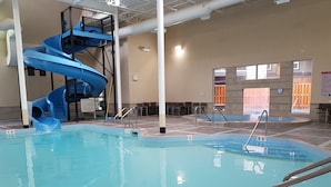 An indoor swimming pool with a blue slide, clear water, and marked depth levels. - Paradise Resort Club and Spa (Canmore)