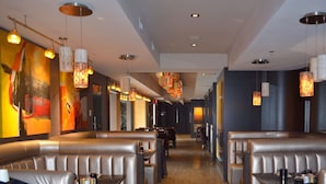 A modern restaurant interior with booth seating, pendant lighting, and colorful artwork on the walls. - Paradise Resort Club and Spa (Canmore)