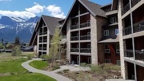 A multi-story hotel with stone facades and balconies, set against a backdrop of snow-capped mountains. - Paradise Resort Club and Spa (Canmore)