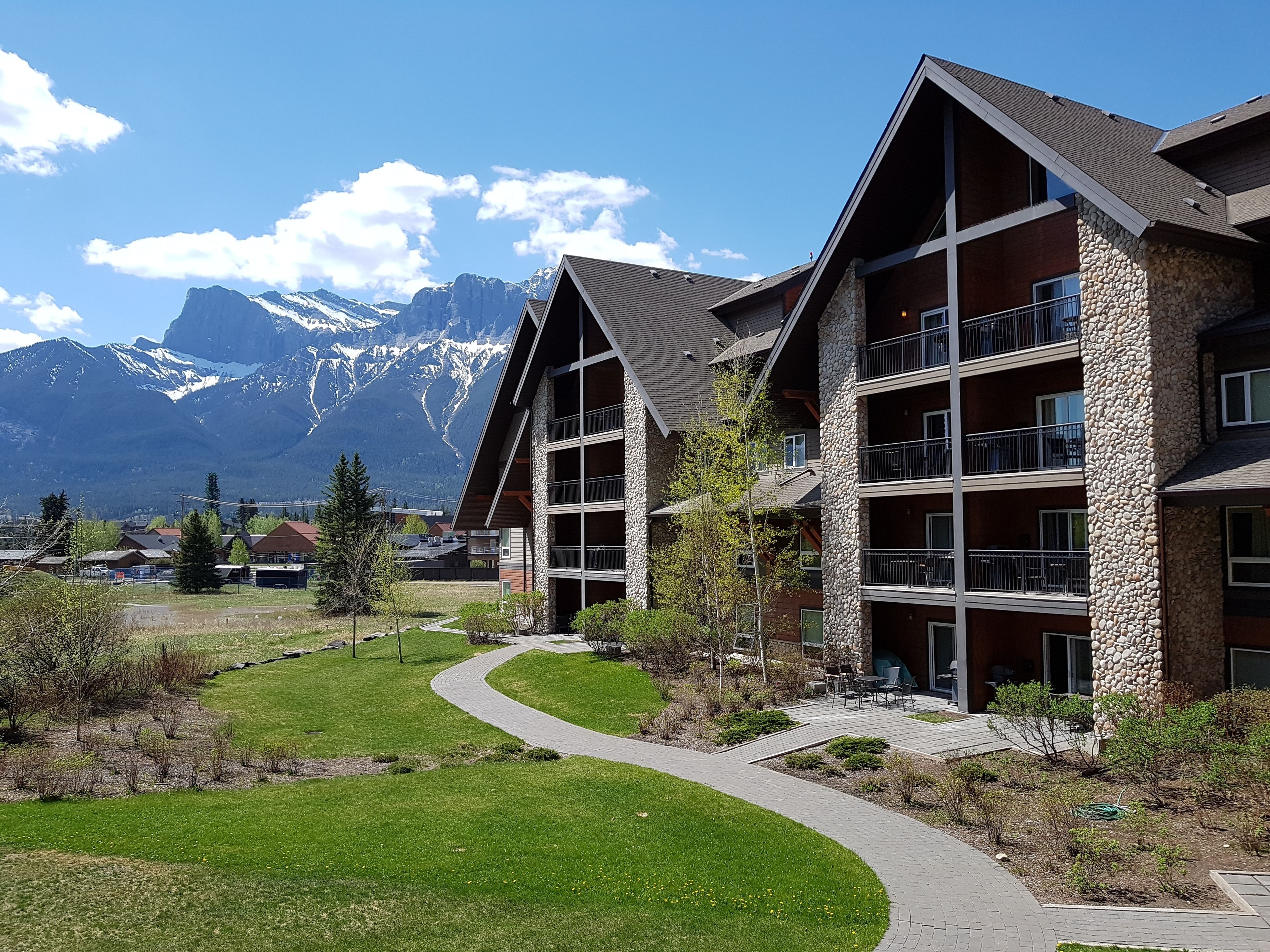 A multi-story hotel with stone and wood exterior, balconies, and a pathway leading to the entrance.