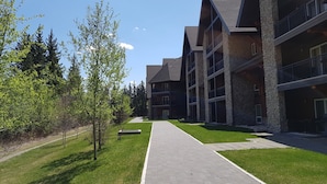 A modern building with multiple balconies and a paved walkway. - Paradise Resort Club and Spa (Canmore)