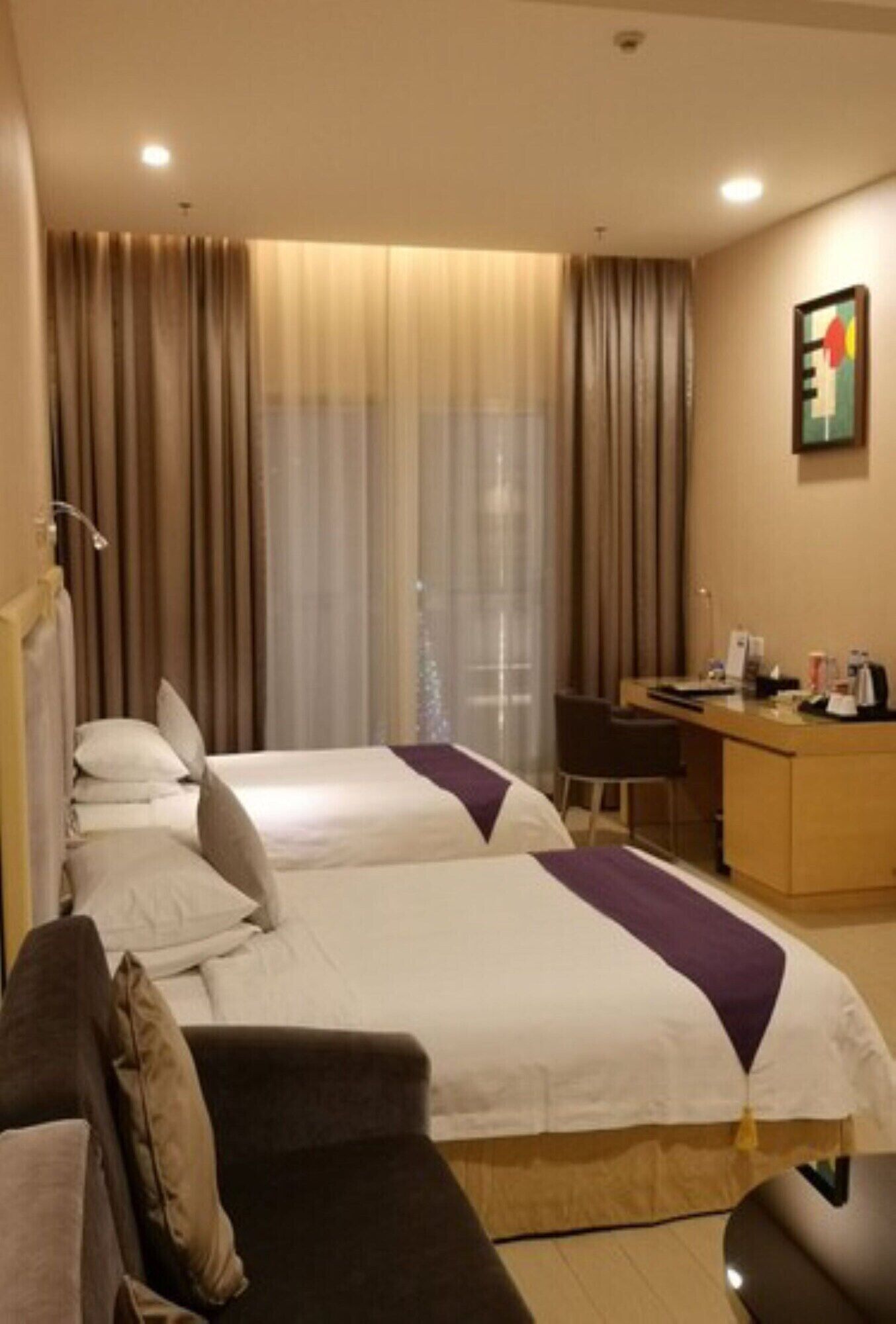 Hotellihuone, jossa on kaksi sänkyä, työpöytä ja tuoli.