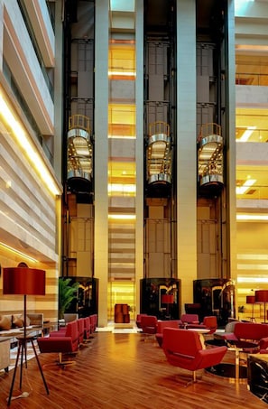 A spacious lobby with high ceilings, red seating, and modern lighting fixtures.