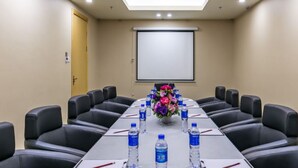 A conference room with a long table, black leather chairs, water bottles, and a floral centerpiece. - The Bauhinia Hotel (Shenzhen)