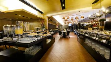 Un área de bufé con varias estaciones de servicio, una gran variedad de alimentos y una decoración interior moderna.