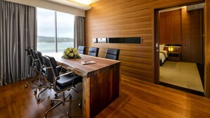 A conference room with a wooden table, black chairs, and a view of the sea through large windows. - Horizon Hotel (Kota Kinabalu)