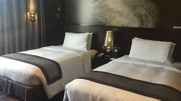 A hotel room with two beds, a nightstand with a lamp, and a large abstract painting on the wall.