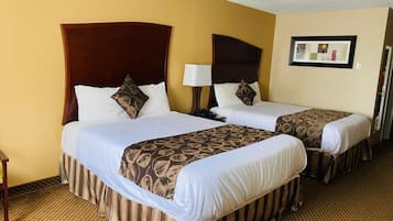 Une chambre d’hôtel avec deux lits, chacun doté d’une tête de lit, d’une table de chevet avec une lampe et d’une couvre-lit à motifs.