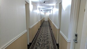 Un pasillo largo y estrecho con alfombra estampada y paredes color crema.