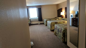 Een hotelkamer met twee bedden, een bureau met lamp, een televisie en een raam met gordijnen.