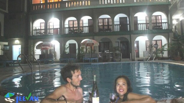 An indoor swimming pool with a two-story building in the background. - Jeevan Ayurvedic Beach Resort (Thiruvananthapuram)