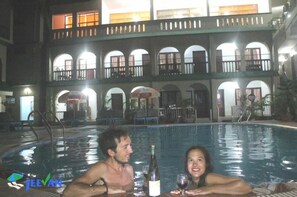 Una piscina interior con un edificio de dos pisos al fondo.