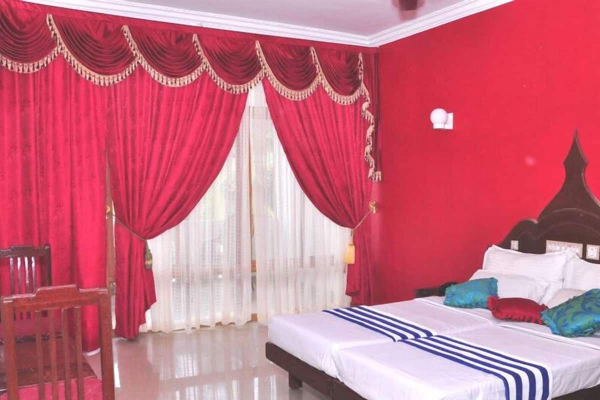 Un dormitorio con una cama grande, cortinas rojas y un cabecero blanco.