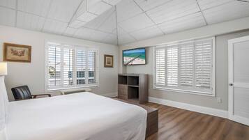 A bedroom with a large bed, a TV mounted on the wall, and a wooden cabinet.