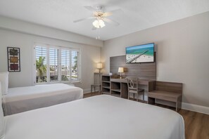 A hotel room with two beds, a desk, a chair, a ceiling fan, and a beach view. - Naples Park Central Hotel (Naples)
