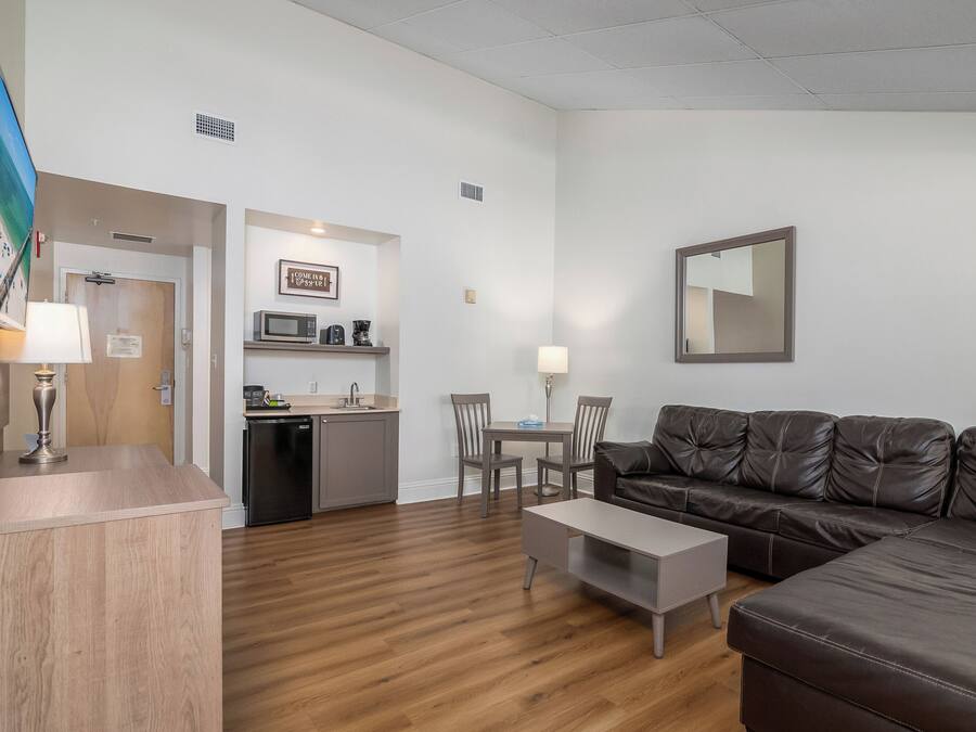A living room with a brown leather sofa, a wooden coffee table, and a dining area with a table and chairs.