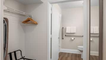 A compact bathroom with a shower, toilet, and a mirror.