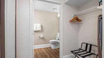 A bathroom with a toilet, a towel hanging on the wall, and a metal drying rack.