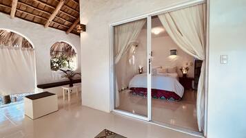 A bedroom with a large sliding glass door, a bed with white bedding, a small bedside table, and a decorative rug.