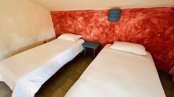 Una stanza con due letti singoli, un tavolino e una parete rossa con una trama decorativa.
