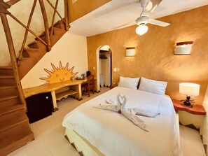 A hotel room with a bed, a desk, a chair, a staircase, and a ceiling fan. - Hotel La Tortuga (Las Terrenas)