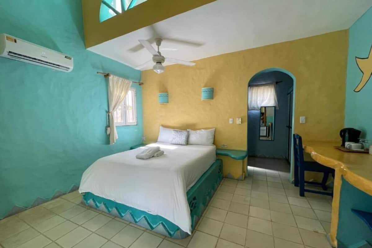 A room with a bed, a desk, an air conditioner, and a ceiling fan.