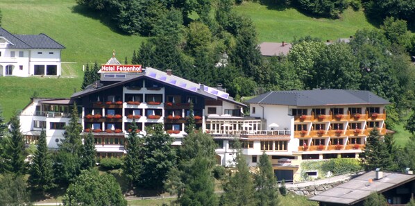 A hotel with multiple balconies, a sign reading "Hotel Felsenhof," and a view of surrounding greenery. - Wohlfühl & Genusshotel Felsenhof (Bad Kleinkirchheim)