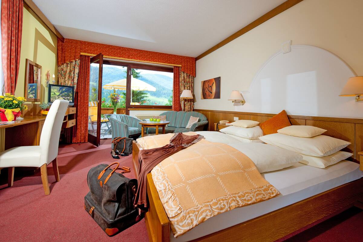 A hotel room with a bed, a desk, a chair, a table, and a view of the outdoors.