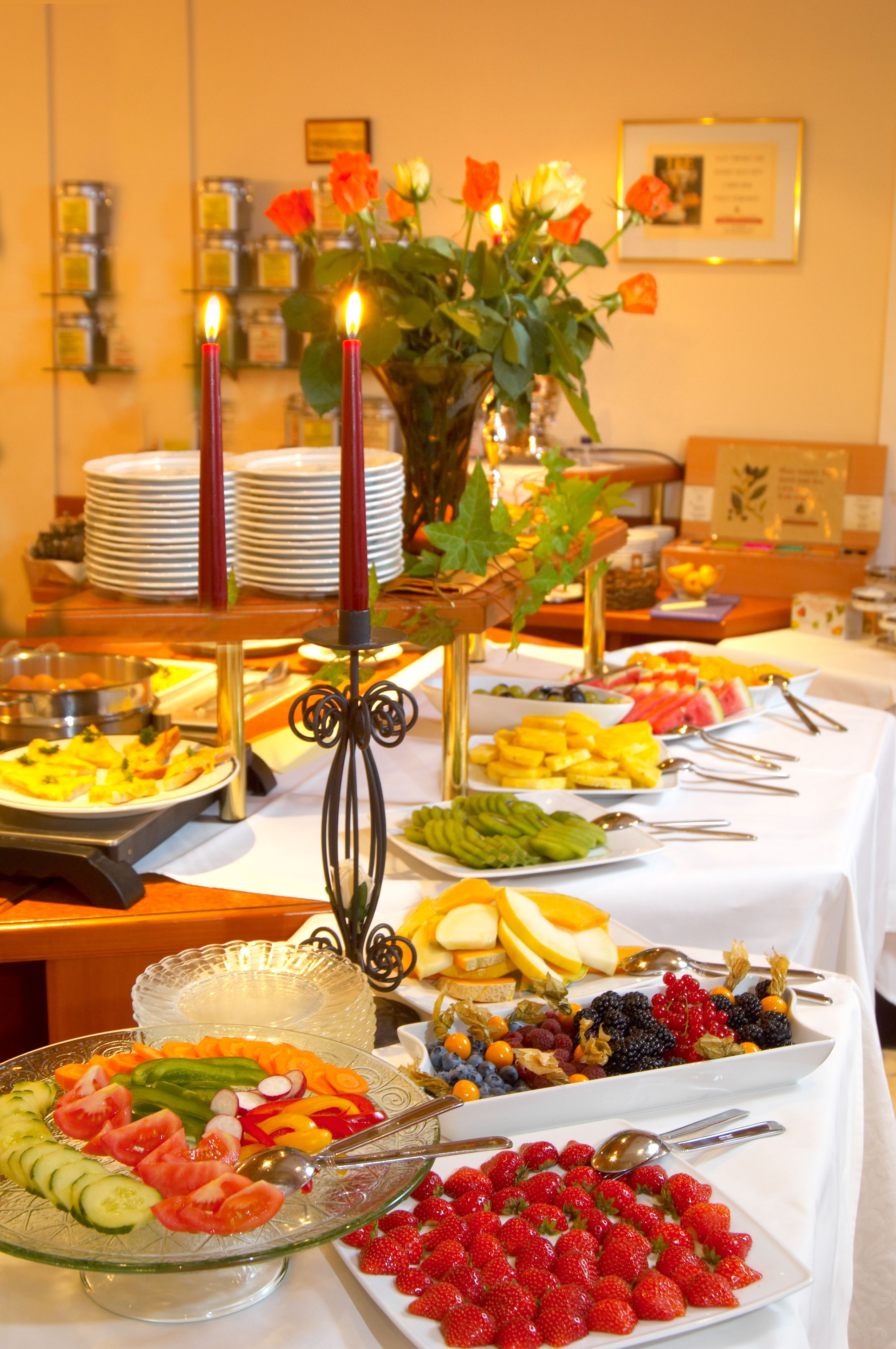 Une table de buffet garnie de divers fruits et légumes, avec un chandelier en guise de décoration centrale.
