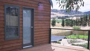 A wooden cabin with a balcony overlooking a rural landscape. - Red Brier Cottage Accommodation (Richmond)