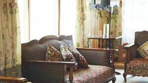 A traditional living room with a sofa, armchairs, and a side table. - Red Brier Cottage Accommodation (Richmond)