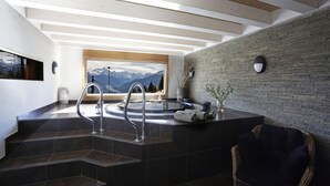 Une salle de bain moderne avec un lavabo en pierre, une vue sur les montagnes et un fauteuil en osier.