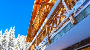 Un bâtiment en bois, doté de balcons couverts de neige, se dressant sous un ciel d’un bleu limpide.