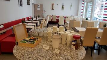 A restaurant with a round table displaying various coffee mugs and a box of chocolates.