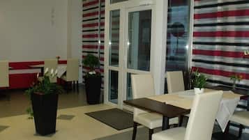 Een hotel lobby met een zithoek, een receptiebalie en een groot raam met gestreepte gordijnen.