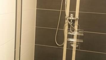 A shower with a handheld showerhead and a wall-mounted faucet.