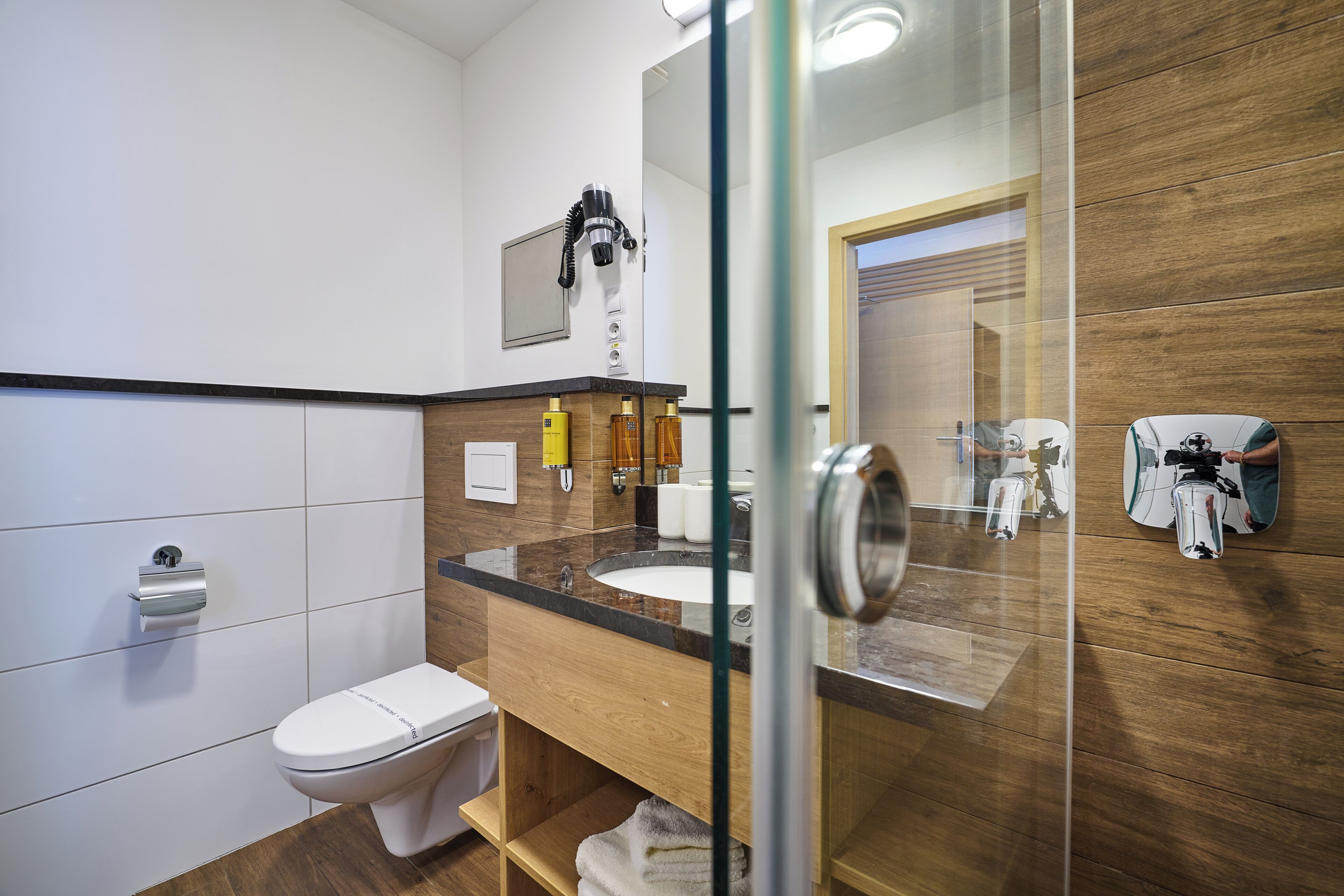 Et moderne badeværelse med toilet, håndvask og bruseområde.