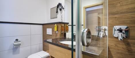 Un baño moderno con inodoro, lavamanos y zona de ducha.