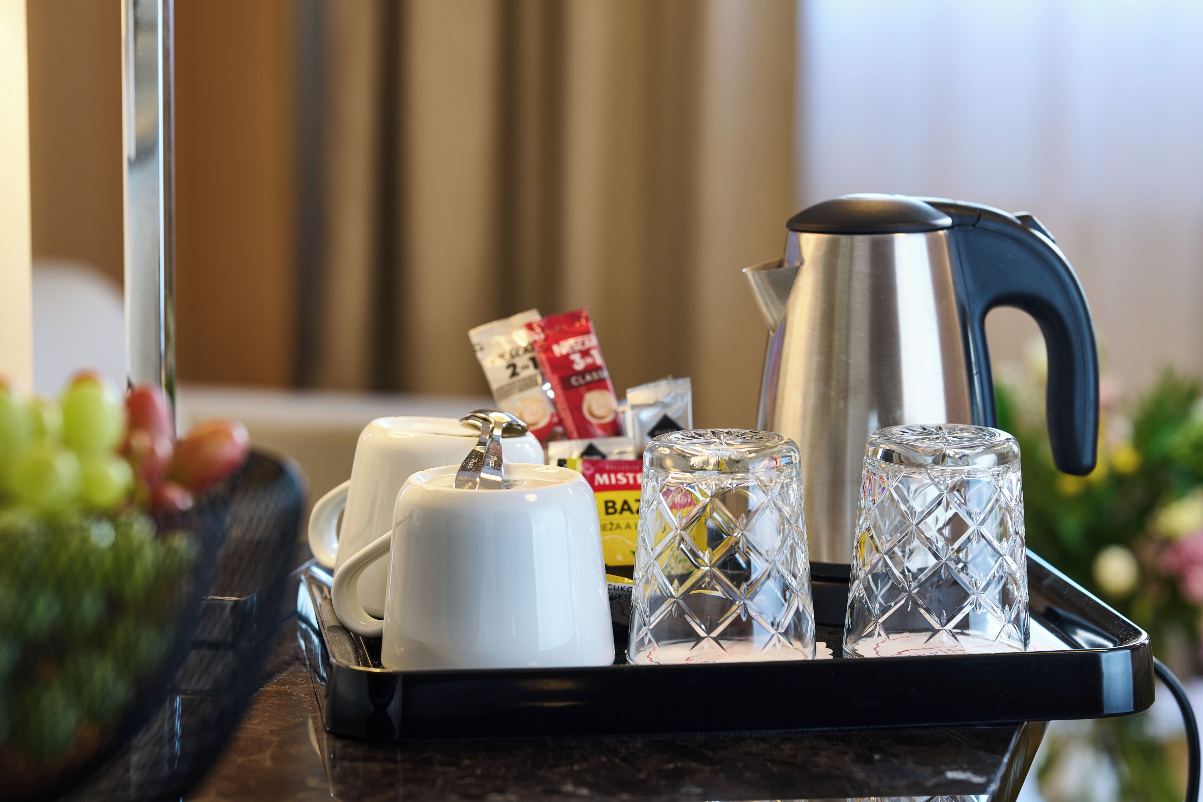 Ein Tablett mit Wasserkocher, Tassen und Gläsern auf einer Arbeitsplatte.