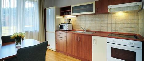 Cocina compacta con armarios de madera, microondas integrado, estufa y pileta.