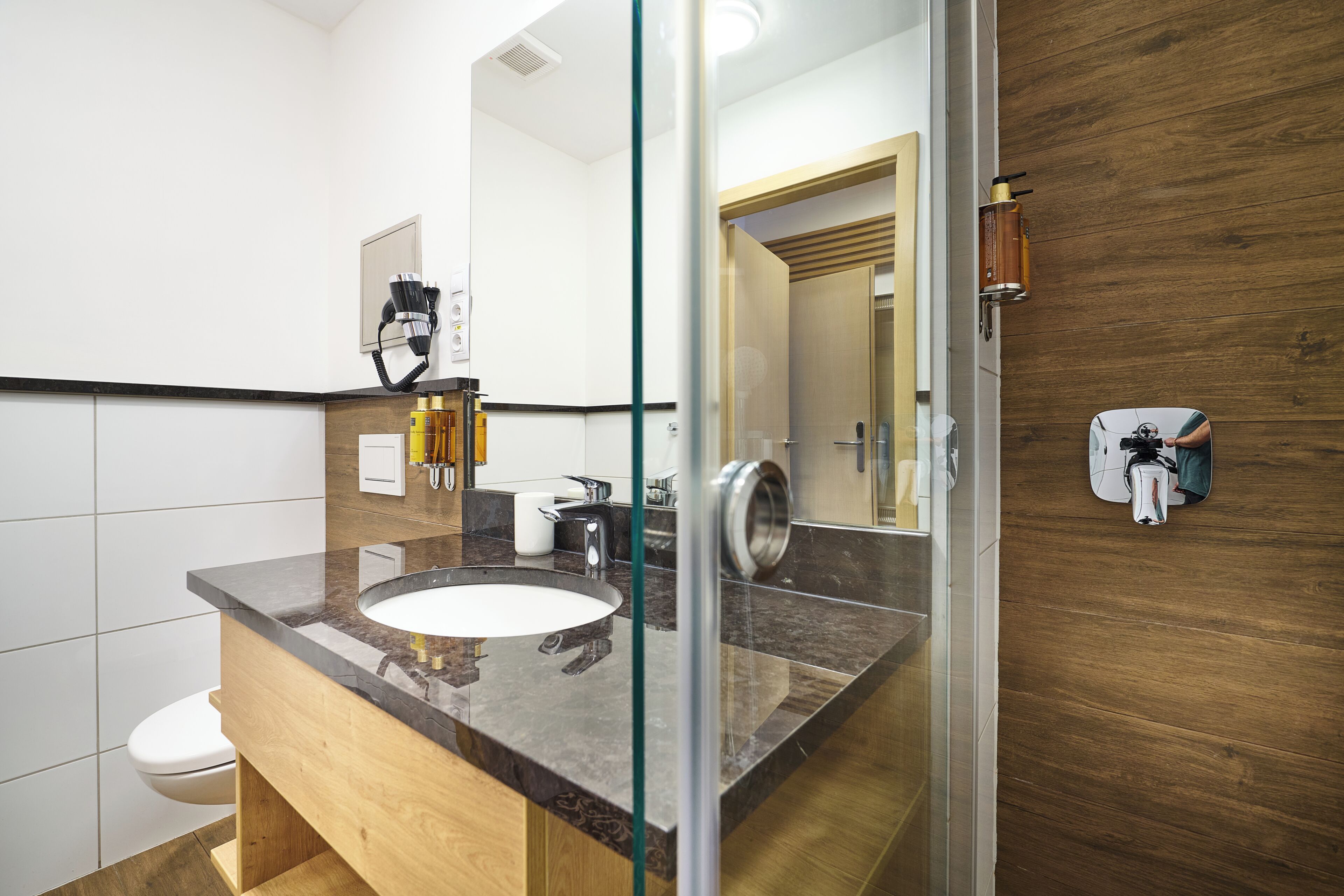 Un baño moderno con cabina de ducha de vidrio, tocador de madera y un espejo grande.