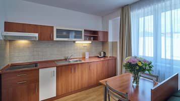 Una cocina moderna con armarios de madera, un lavamanos de acero inoxidable y una zona de comedor con mesa y sillas.