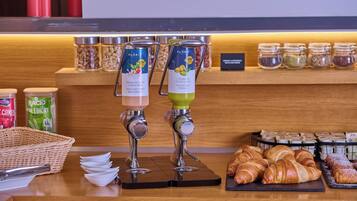 Een ontbijtstation met twee koffieautomaten, diverse soorten beleg en een keuze aan gebak.