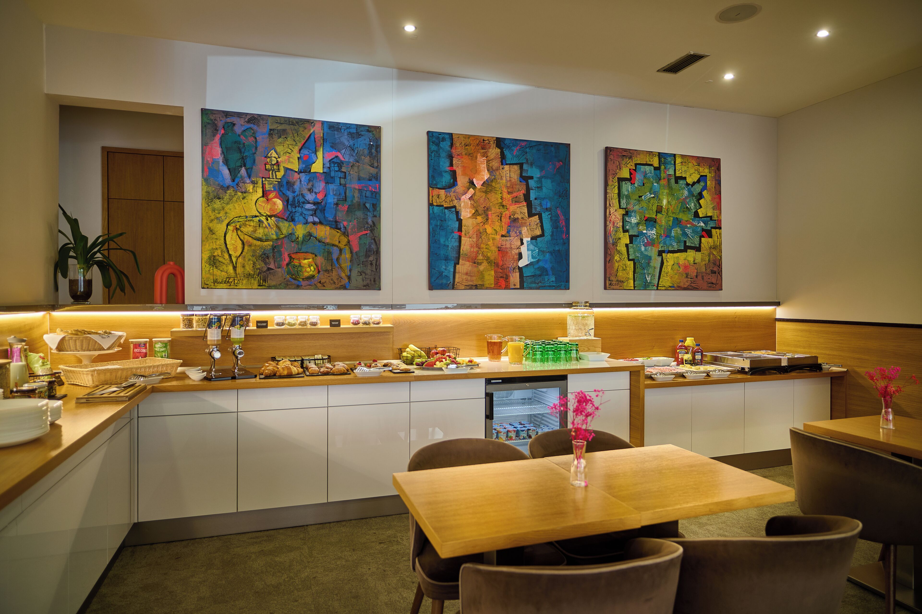 Eine moderne Hotelhalle mit einer zentralen Rezeption, einer Sitzecke und abstrakter Kunst an den Wänden.
