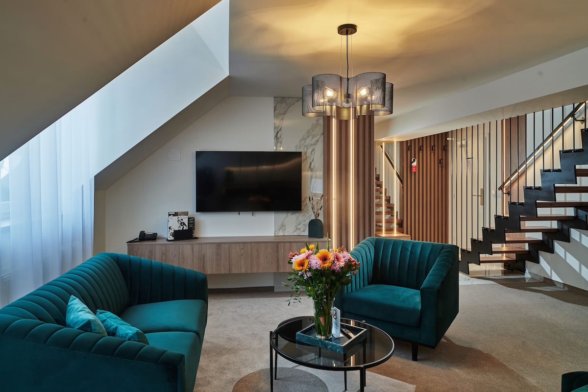 A modern living room with teal sofas, a glass coffee table, and a decorative vase.